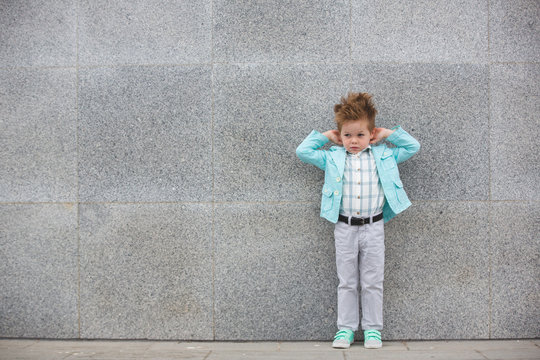 Fashion kid posing near gray wall