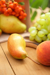 Pears, peach, green grapes, rowan berries in a wooden box on a wooden table in the woods at the time of harvesting