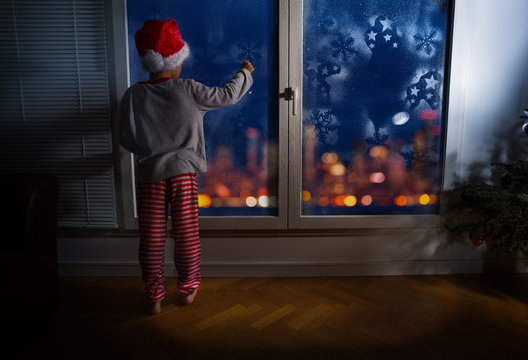 Boy on New Year night in front of frosty window