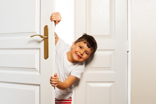 Little Boy Looks Behind Room Door With Smile