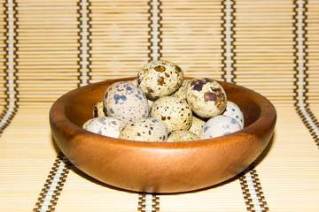 quail eggs in a wooden bowl on a napkin from natural bamboo.