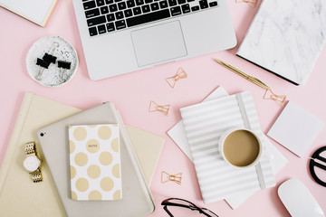 Flat lay modern workspace with laptop, notebook and stationery on pastel pink background. Top view....