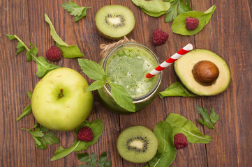 healthy green smoothie with banana, spinach, avocado and kiwi in a glass bottles on a rustic