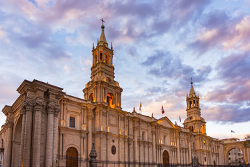 Fototapeta na wymiar Stunning colorful sky and clouds at dusk in Arequipa, famous travel destination and landmark in Peru. Wide angle view from below of the colonial Cathedral. Panoramic frame.