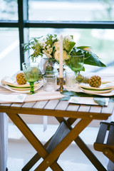 table decorated with plates, pineapples, candles and flowers, green and white colour