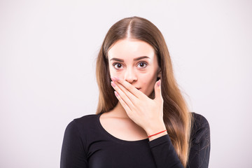 Close-up portrait of surprised attractive woman covering her mouth by the hands, over white...