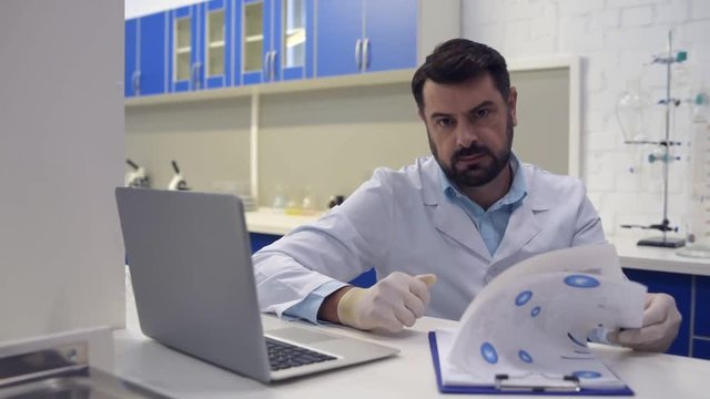 Friendly looking scientist smiling into camera while working