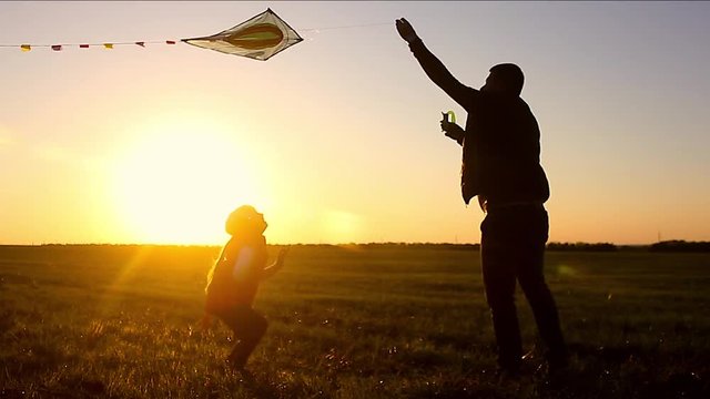 happy family father and baby daughter launch a kite on meadow