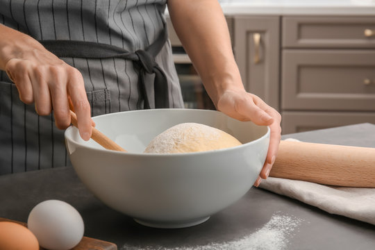 Female chef with dough in bowl on kitchen table
