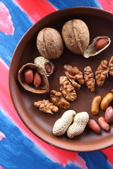 Walnuts and peanuts on a brown clay plate on a pop art background