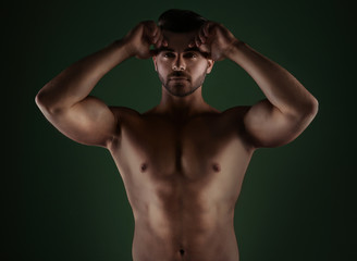 Sporty young man on dark color background