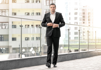 Handsome man in elegant black suit outdoors