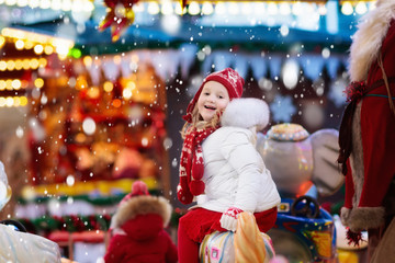 Fototapeta na wymiar Child on Christmas fair. Kid riding Xmas carousel