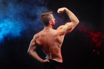 Muscled male model posing. Young powerful man with perfect body, view from the back