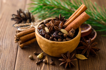 Set of spices for mulled wine in ceramic bowl on wooden table.