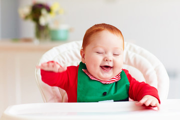 cute happy infant baby boy in elf costume sitting in highchair