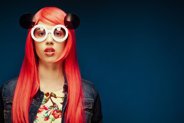 fashion girl with pink hair and big sunglasses over blue  background