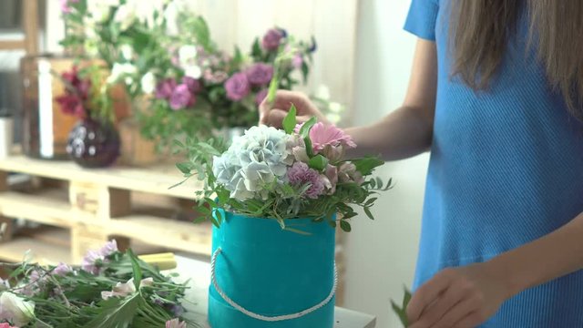Young 20s girl florist makes a flower hat box in her flower shop close-up 4k.