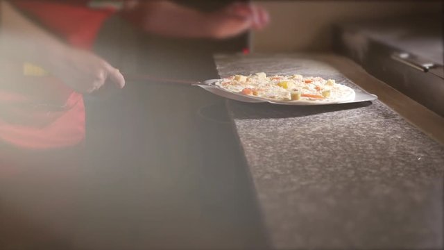 The cook puts pizza on a shovel to put pizza in the oven. 4K.