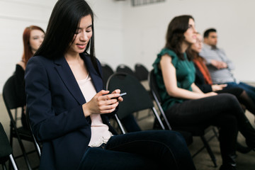 Young woman using a smart phone in an auditorium