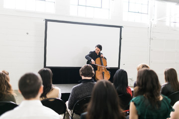 Young man on stage playing the cello