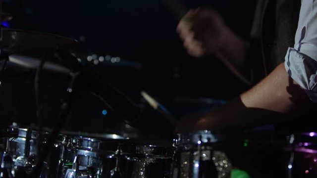  Close up on hands of drummer playing with a band at live music event.