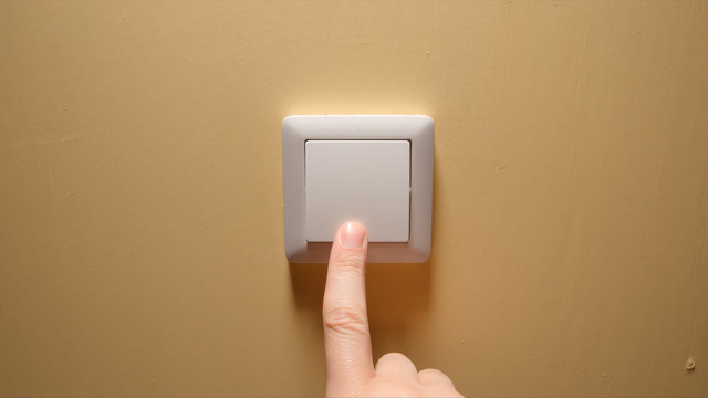 Human Hand Turn Off A Power Button On A Yellow Wall