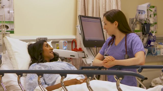 Nurse delivers good news to a female patient in hospital bed.