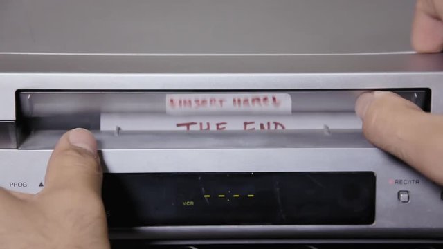 Inserting and removing a VHS tape from a VCR. The title says The end.
