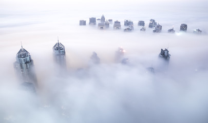 World's tallest skyscrapers surrounded by dense fog on a winter morning. Dubai, UAE.