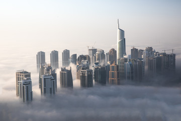 World's tallest skyscrapers surrounded by dense fog on a winter morning. Dubai, UAE.