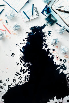 Writer workplace with spilled ink, crumpled paper, scattered letters, papers and notepads on a white wooden background. Header with creative writing concept. Flat lay with copy space.