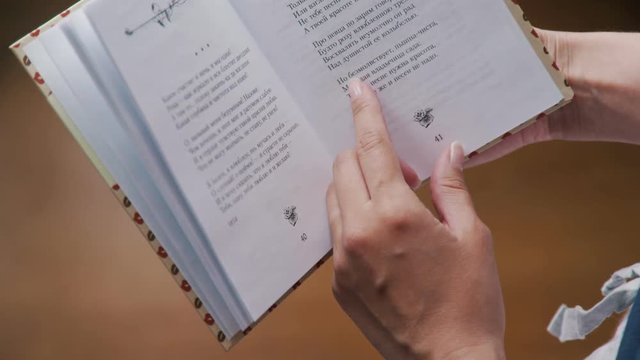 A cozy evening with a book under a rug: women's hands hold a book, a page with poems is open. Reading a book under a blanket. Poen book with poem