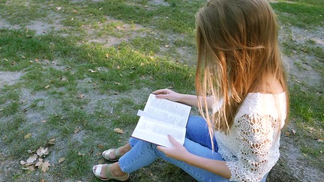 4k. Bible  and attractive girl in sunny park. Christian prayer team shot
