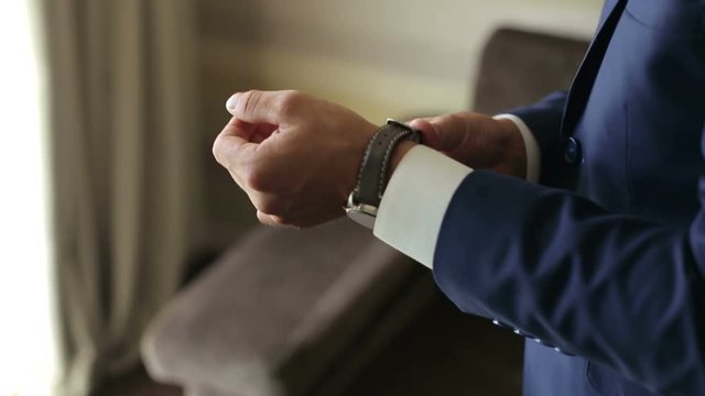 Elegant man puts on a clock on hand, close-up. Elegant businessman dressed clock before meeting with partners.