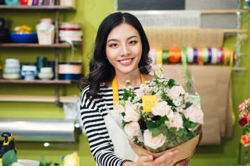Beautiful asian female florist holding bouquet of flowers