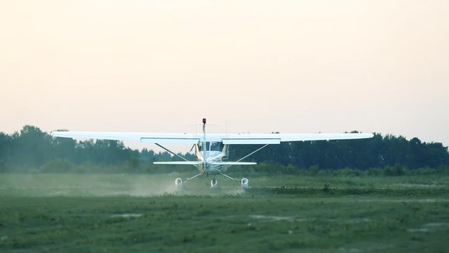 The plane will accelerate before take-off from a grassy airstrip, surrounded by trees, showcasing the excitement of aviation and the beauty of flight in a serene environment