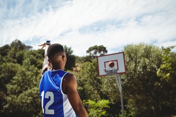 Rear view of male teenager practicing basketball