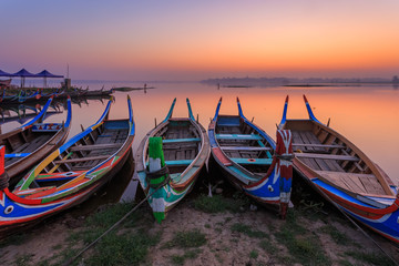 Traditional Painted Wooden Boats waiting tourists or passengers  on lake at sunrise or sunset in Mandalay at U-Bein Bridge, Amarapura, Mandalay, Myanmar (Burma)