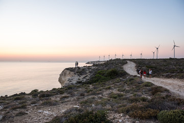 Unidentified people wait for sunset and wind tribunes on the background.Bozcaada,Turkey:21 August,2017