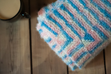 The knitted plaid of a multi-colored wool. Handmade. Heat of the home. Plaid and a cup of coffee or cocoa