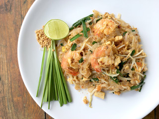 Pad Thai, stir-fried rice noodles with shrimp in white plate on wood table. The one of Thailand's national main dish. the popular food in Thailand. Thai Fried Noodles