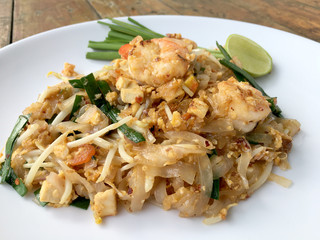 Pad Thai, stir-fried rice noodles with shrimp in white plate on wood table. The one of Thailand's national main dish. the popular food in Thailand. Thai Fried Noodles