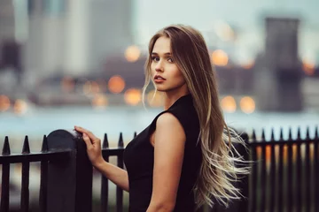 Foto auf Acrylglas Gorgeous young model woman with perfect blonde hair looking at camera posing in the city wearing black evening dress. © Nick Starichenko