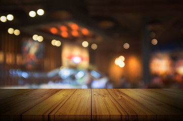 Empty wooden table top with blurred restaurant or cafe light background.