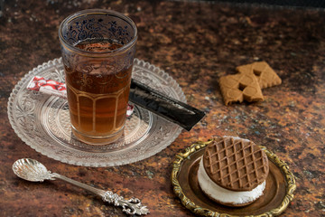 starker heißer Tee im Glas mit einem Keks mit Eiscreme gefüllt
