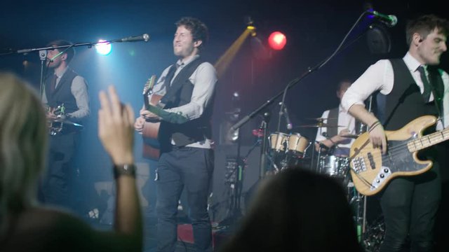  Live band performing in front of an enthusiastic crowd at music event.