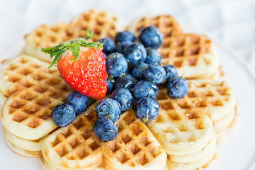 Fresh homemade heart shape waffles with blueberries and strawberry, close up