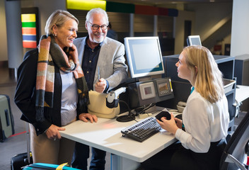 Business Couple Looking At Staff Holding Passport At Airport Che