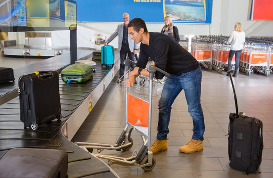 Man Waiting For Luggage From Conveyor Belt At Airport